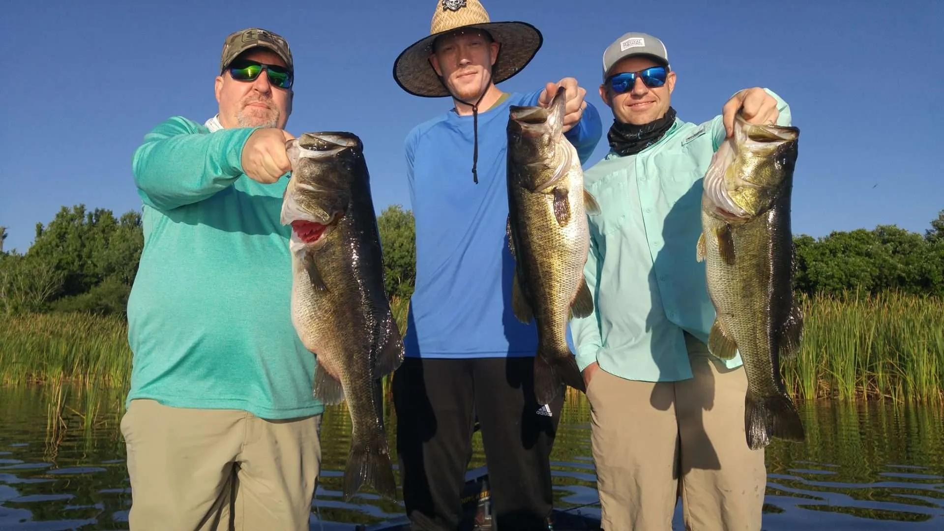 Anglers holding a largemouth bass caught on Lake Tarpon